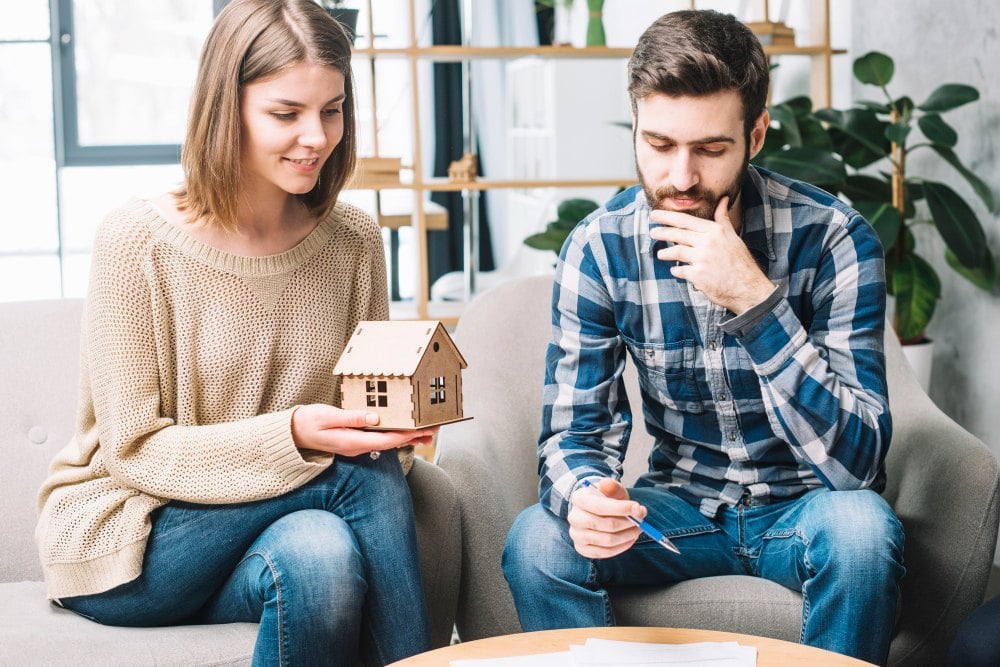 Couple on sofa holding house model planning a home sale