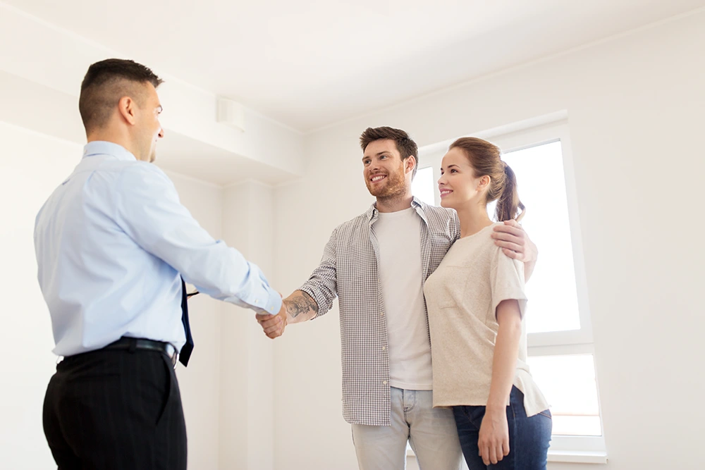Cash buyer shaking hands with happy couple after home deal