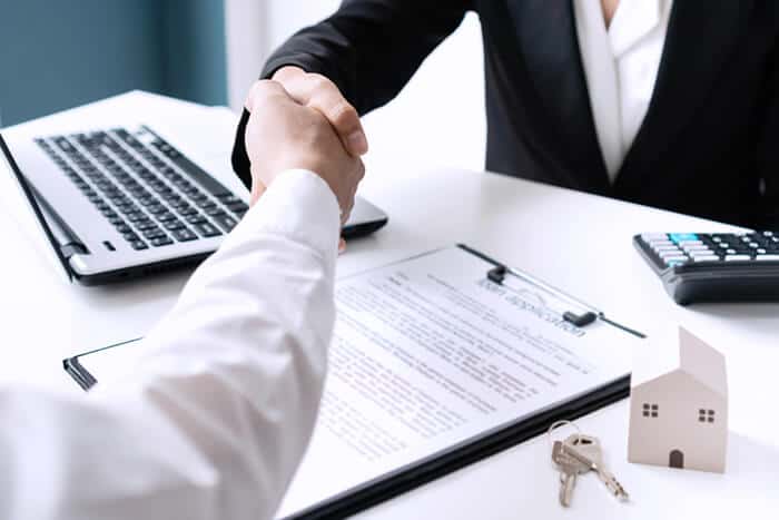 Handshake over contract with house keys to close home deal